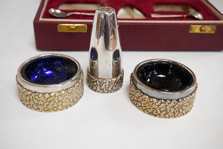 A cased Elizabeth II parcel gilt silver three piece cruet set, with textured band and two matching spoons, by Mappin & Webb, Birmingham, 1972, pepper 72mm. Condition - fair to good